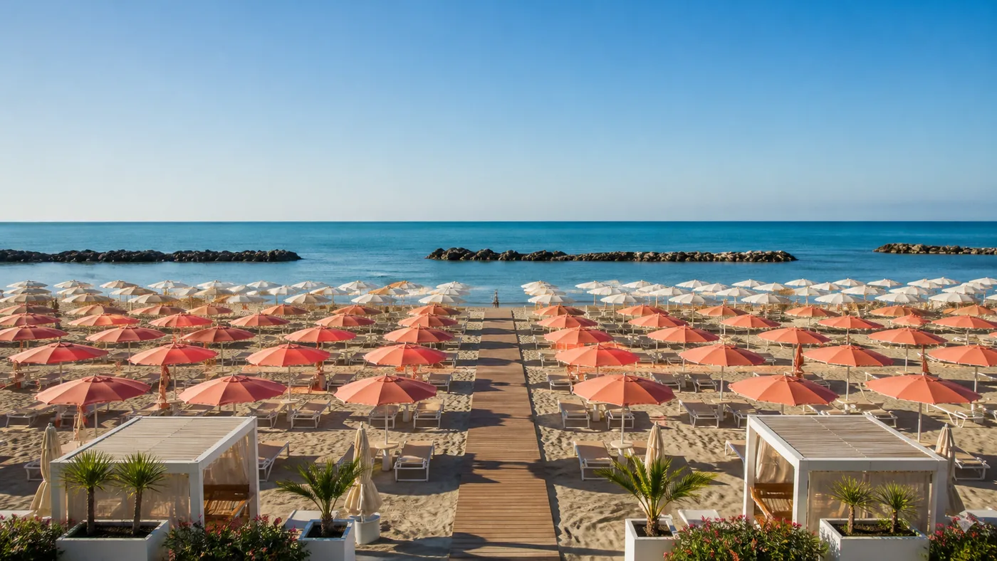 Stabilimento balneare con file ordinate di ombrelloni e passerella verso il mare