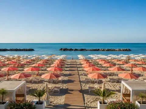 Stabilimento balneare con file ordinate di ombrelloni e passerella verso il mare